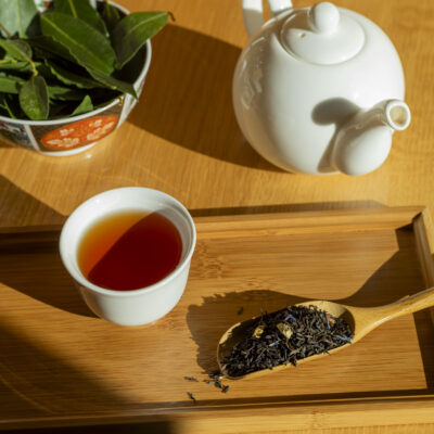 Foglie di tè, sullo sfondo una tazza di tè e una teiera