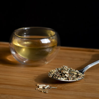 Un bicchiere di tisana e un cucchiaio di foglie asciutte