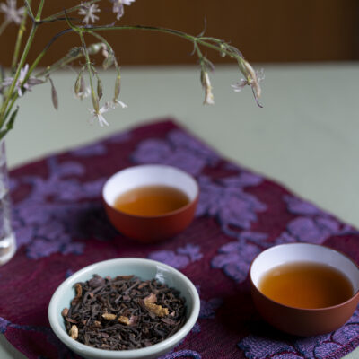 Foglie di tè e sullo sfondo due tazzine di tè