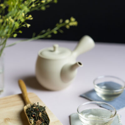 Foglie di tè, sullo sfondo fiori, una kyusu e due tazzine