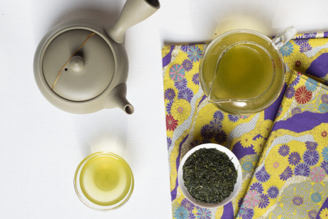 Foglie di tè, una tazzina e una brocca di tè e una kyusu riparata con il kintsugi