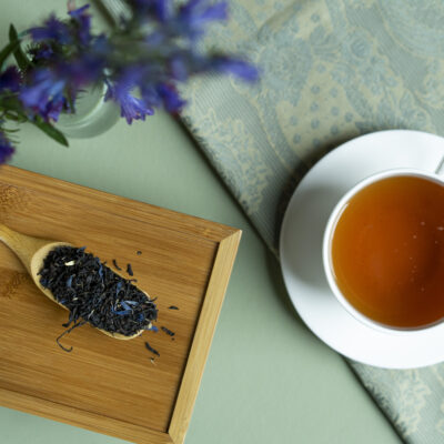Una tazza di tè caldo e un cucchiaio di legno colmo di foglie di tè