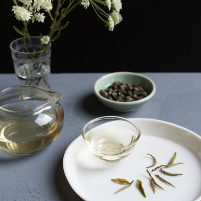 Foglie di tè aperte dopo l'infusione, una brocca e una tazzina e tè in foglia