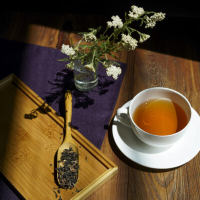 Foglie di tè e zeste di bergamotto, una tazza di tè e fiori di achillea