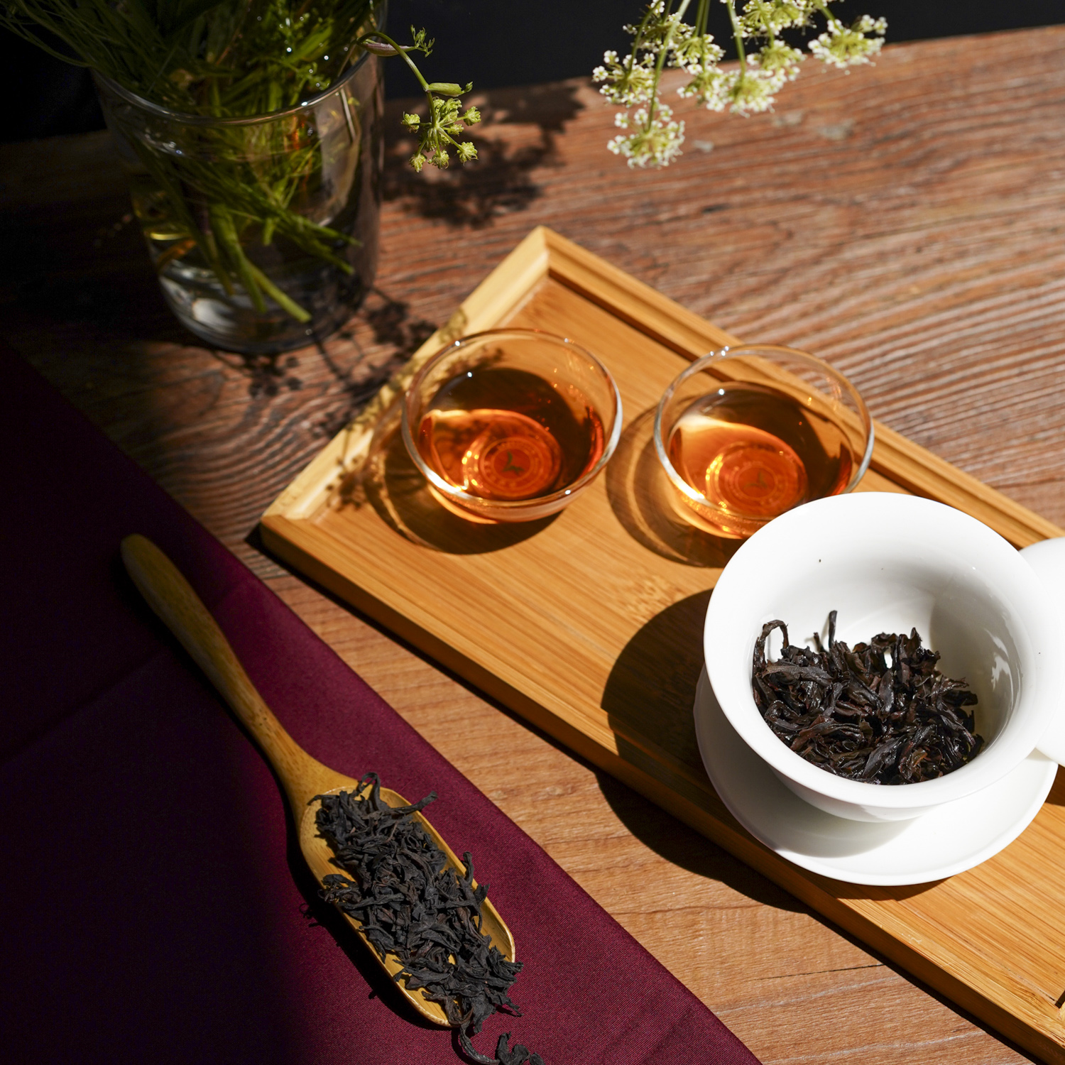 Gaiwan aperta, due tazzine di tè e foglie asciutte in un cucchiaio di legno