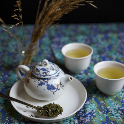 Una teierina, due tazzine di tè caldo e un cucchiaio di foglie di tè asciutte