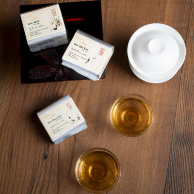 Tre pacchettini di tè, una gaiwan e due tazzine con del tè pronto