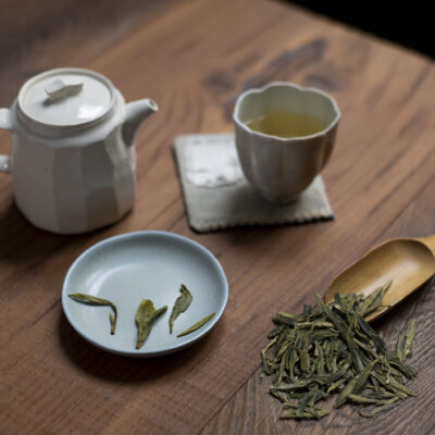 Foglie di tè, foglie bagnate, una tazzina e una piccola teiera