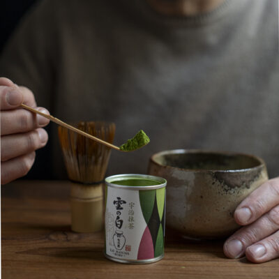 Un cucchiaino colmo di matcha sospeso sopra la chawan